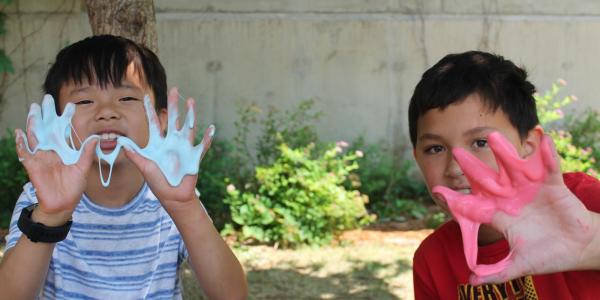 2 boys holding up their slime covered hands 