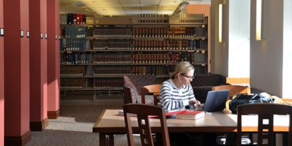 Female student studying at a table in the law library