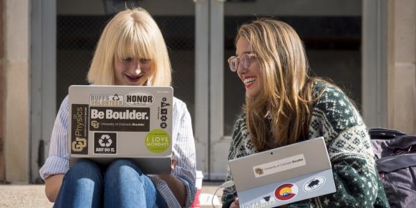 Two female students studying outside on their laptops at CU Boulder