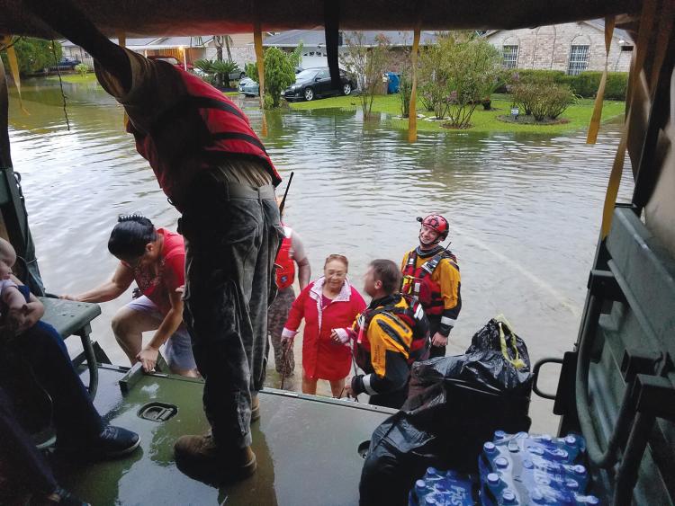 Rescuers assisting individuals standing in a flooded street