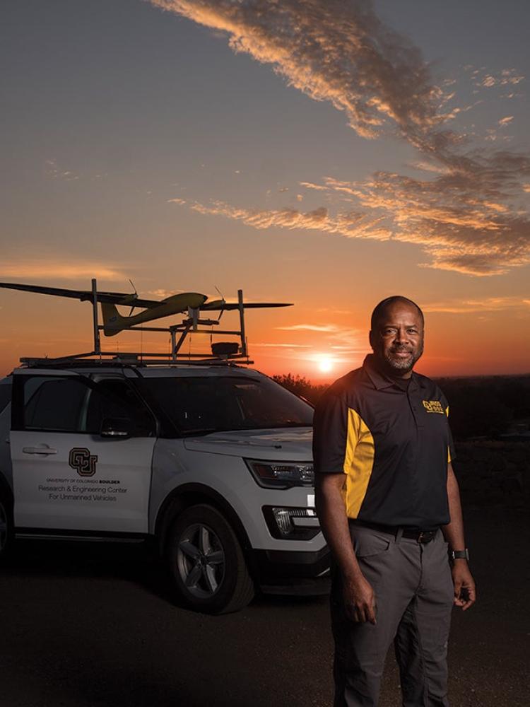 Brian Argrow next to drone on roof of car at sunset