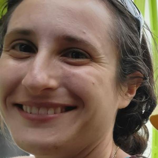 A picture of Arielle Blum, a white woman with long, curly brown hair, smiling.