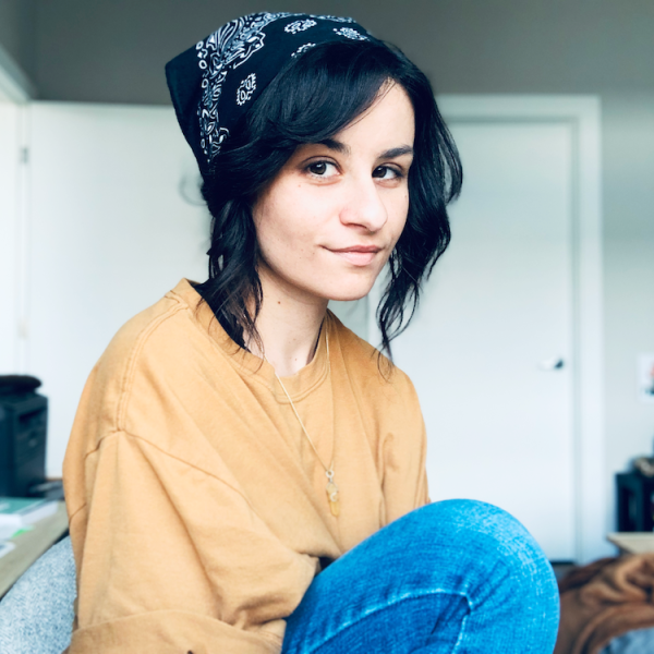 Photo of dana, a light-skinned young woman with short dark hair and wearing a baggy, orange T-shirt and a black bandana.