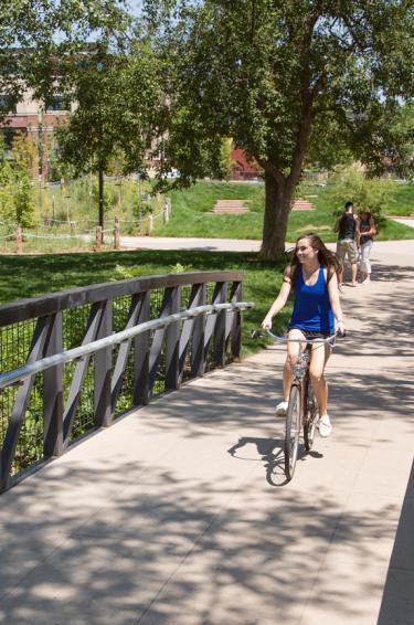 A student riding a bike on a bridge.