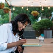 Student sitting at a table writing on a tablet