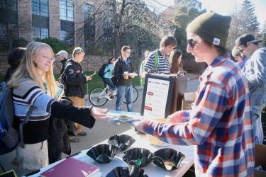 Environmental Center student volunteer exchanges email sign-up sheet with another student at a tabling event