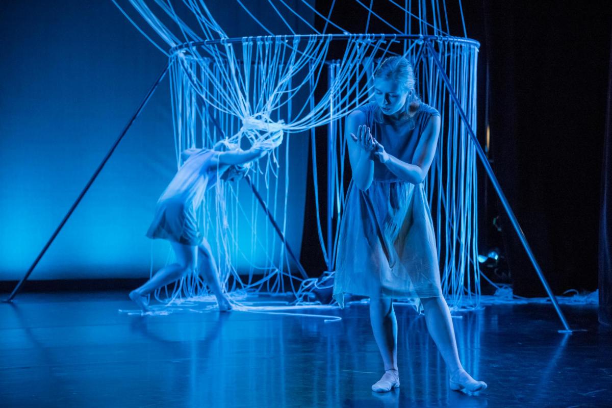Students performing a dance composition in a blue lit theatre