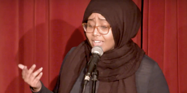 Woman in a hijab speaking in front of a mic