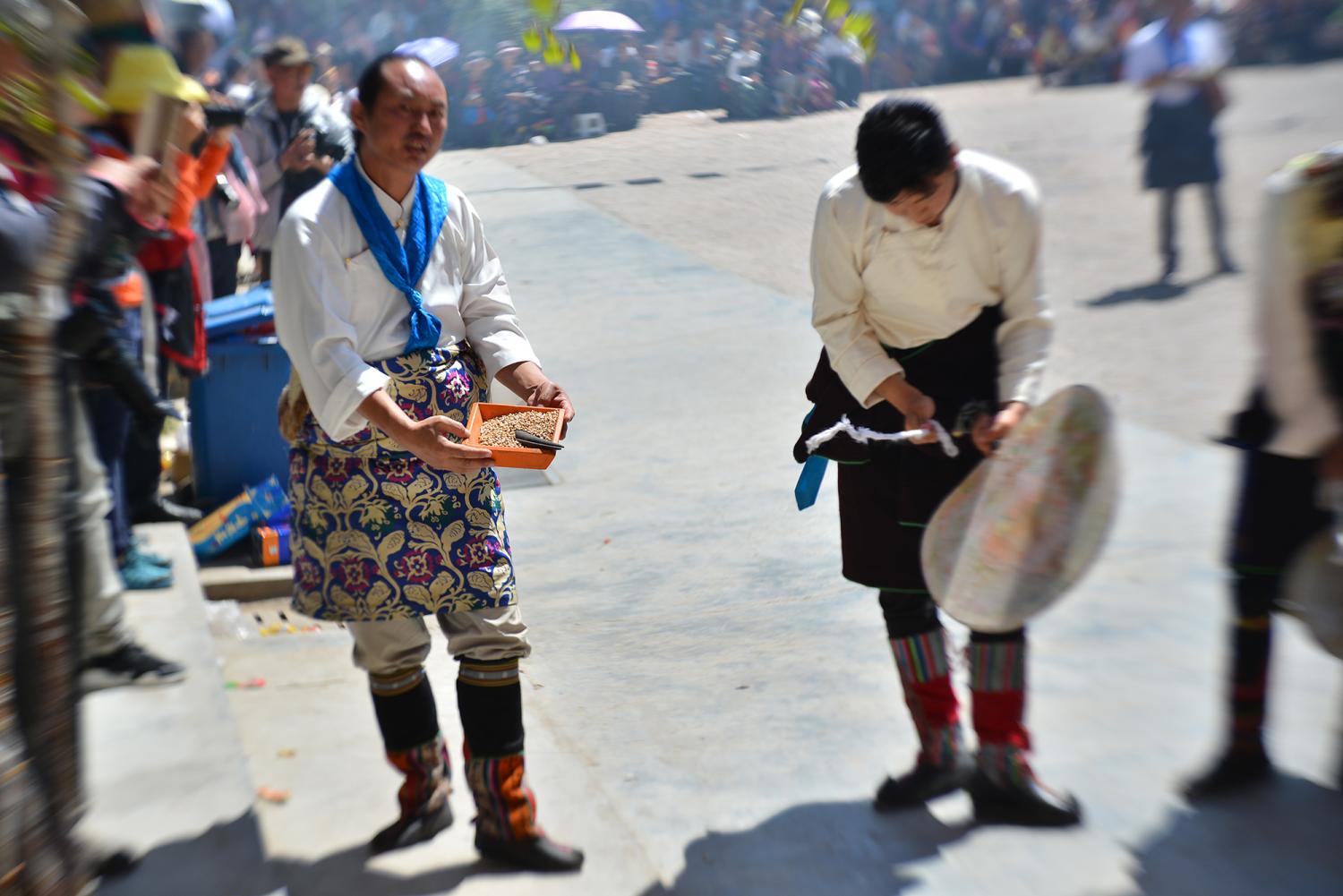 The La ba is pictured at left, holding a box of grain. He will shout and sputter his lips for the entire day as he carries out a number of ritual activities.