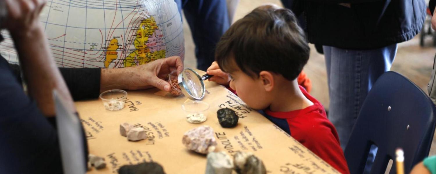 Child analyzes rocks under a magnifying glass