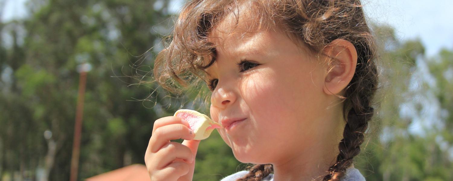 A girl eats a marshmallow.