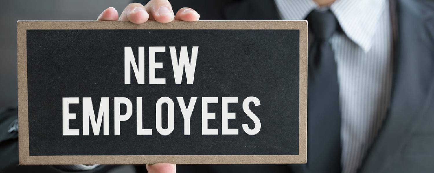 A hand holds a sign that reads "new employees"