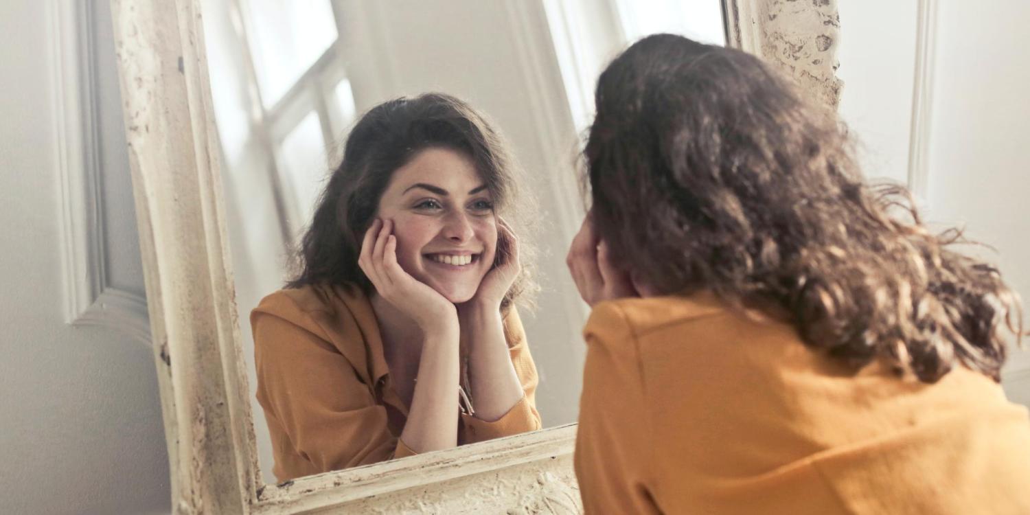 single person smiling at self in mirror