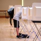 Two people stand at separate voting booths. (Glenn Asakawa/University of Colorado Boulder)