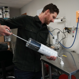 Researcher handles large syringe filled with oxygen microbubbles