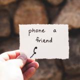 Stock image of a person holding a note saying "Phone a friend"