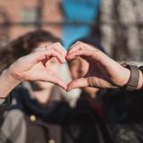 A couple forms a heart, each using one hand (Unsplash/Matt Nelson)