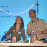 Two faculty members present an electrical light-based experiment.