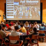 New students, families and volunteers sit at tables during Fall Welcome