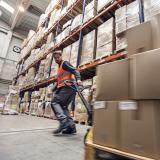 A person pulls a pallet of boxes through a warehouse