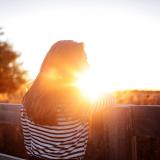 Woman standing on a footbridge at sunset