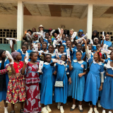 Women and girls in Cameroon excitedly holding biodegradable menstrual pads