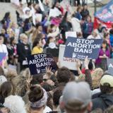 Demonstrators hold up signs at a Stop Abortion Bans rally