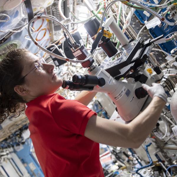 Astronaut in space station using scientific equipment