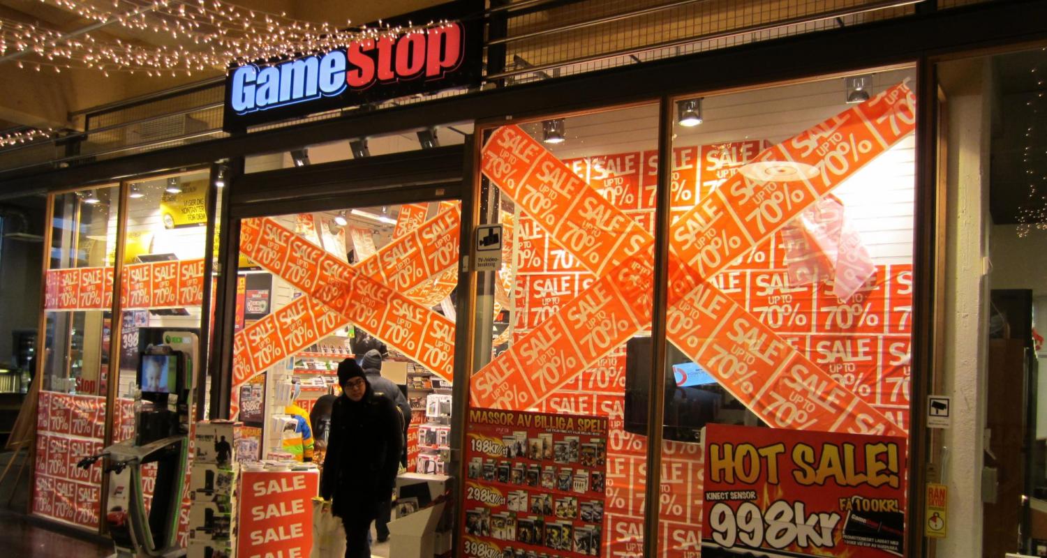 The window of a GameStop store with signs advertising a sale