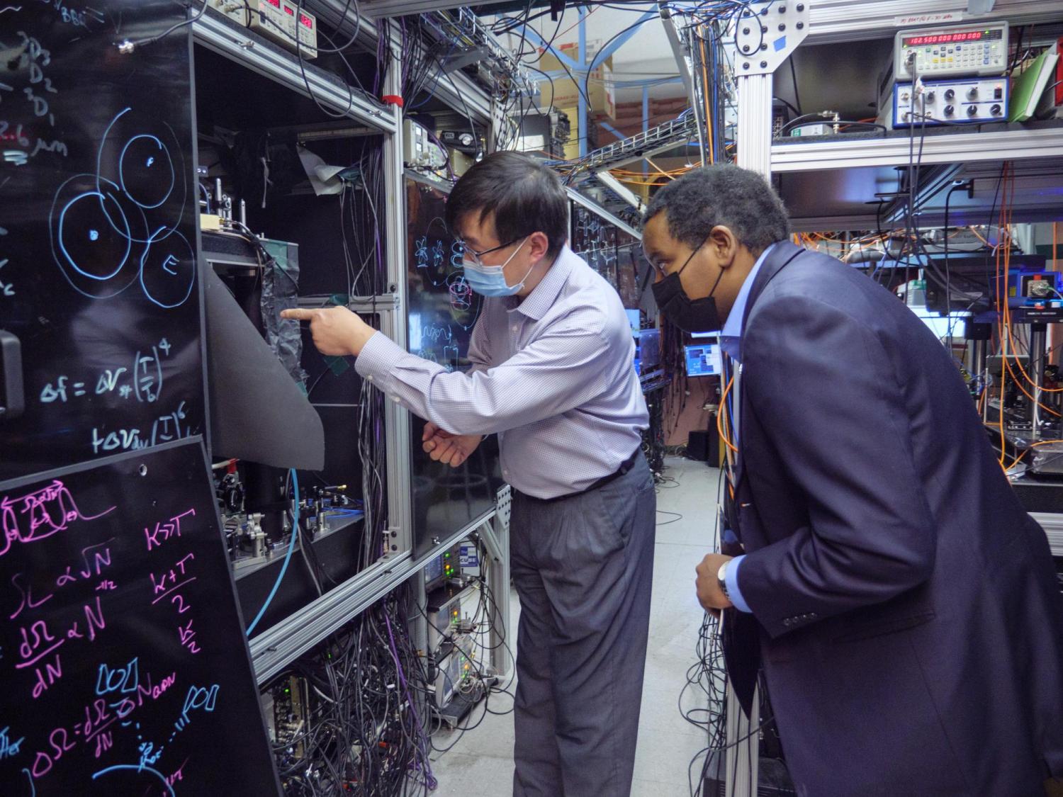 Jun Ye shows U.S. Rep. Joe Neguse his lab