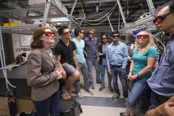 Murnane and students talk in the lab wearing safety goggles