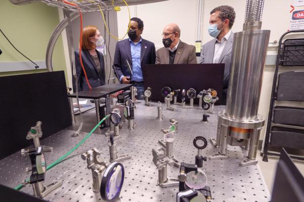 Margaret Murnane, Joe Neguse, Philip DiStefano and Todd Saliman inspect equipment in a lab