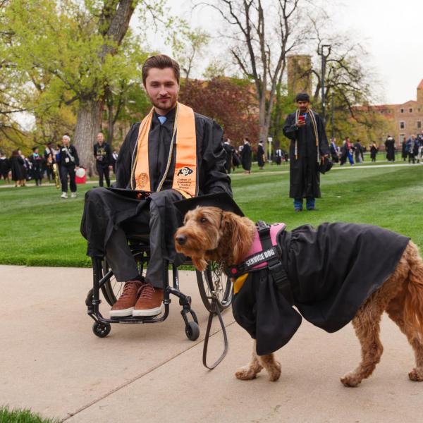Graduate and service dog gather on Norlin Quad before commencement