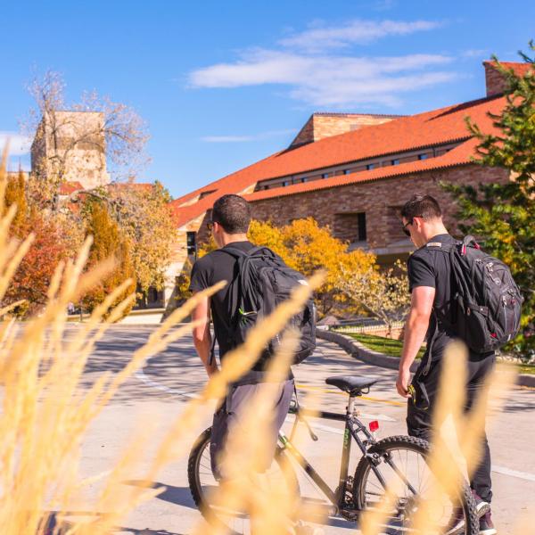 Two students walk their bikes to class during a beautiful autumn day on campus. Photo by Patrick Wine.