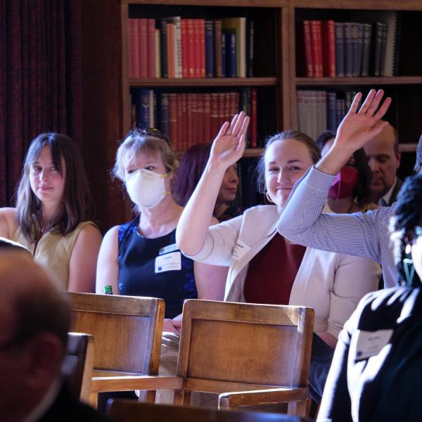 Student researchers raise their hands to be recognized during the EU visit.