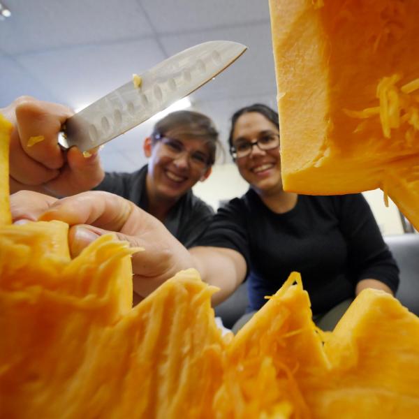 Chantal Lehl, right, and Vanessa Luna carve out their entry in the engineering college's pumpkin carving contest. Photo by Glenn Asakawa.