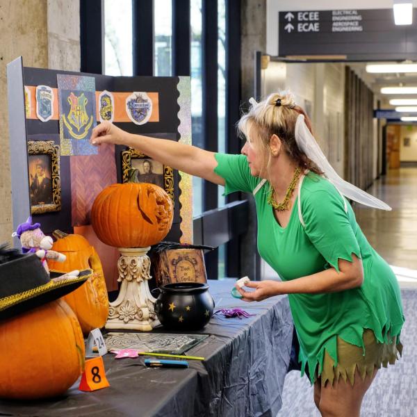 Susan Lelger adds pixie dust to her department's Harry Potter-themed entry in the pumpkin carving contest. Photo by Glenn Asakawa.