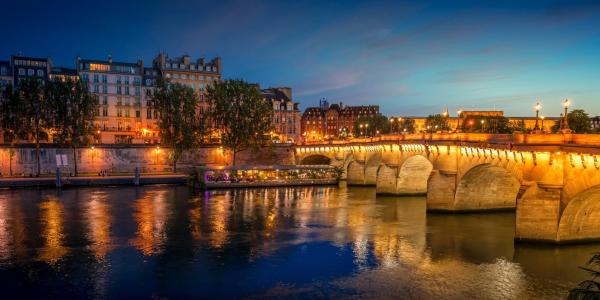 Pont Neuf bridge and Cite island over Seine river at night in Paris