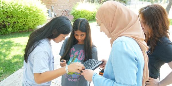 PhD student Kawther Rouabhi helping two high school students troubleshoot their camera.