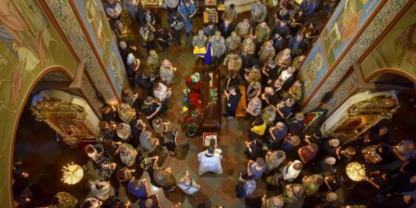 Ukrainians stand over a casket in a church