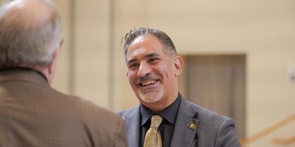 CU Boulder Chancellor Justin Schwartz interacts with a person standing before him. 