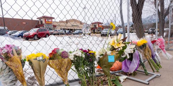 Flowers line a fence surrounding the parking lot where 10 adults, including a police officer, were shot by a lone gunman at the King Soopers at 3600 Table Mesa Dr. (Photo by Glenn Asakawa/University of Colorado)