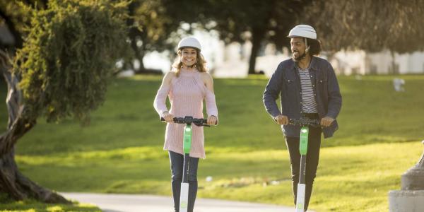 Two people riding Lime scooters