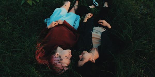 Two people lying in grass together