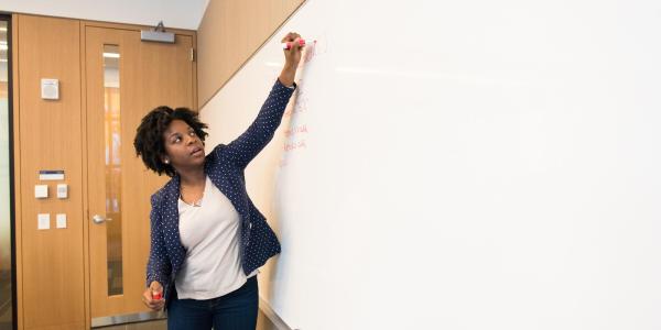 A woman writing on a dry erase board