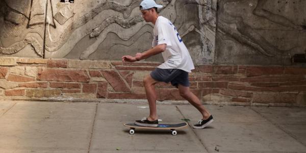 Student riding a skateboard on campus