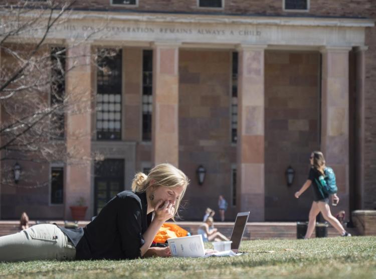 Graduate student studies on lawn outside of Norlin Library