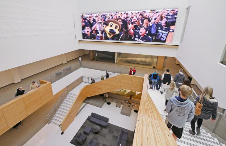 Campus community members walk down stairs in CASE building