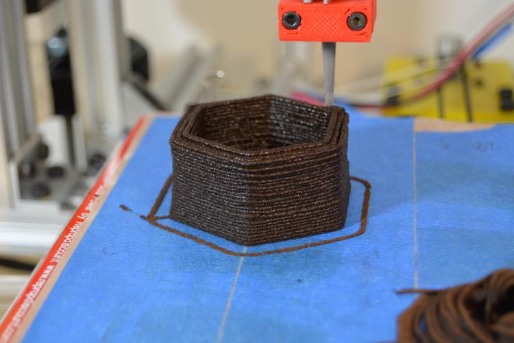 A 3D printer lays down used coffee grounds to make a flower planter. 