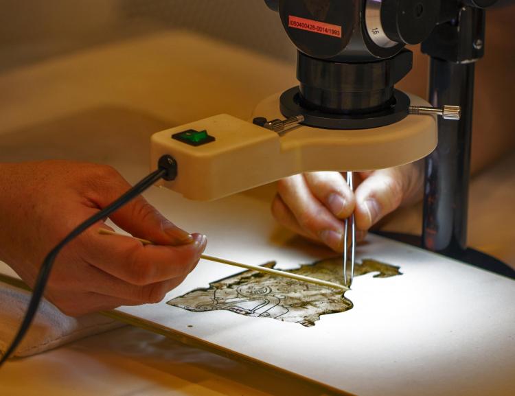 Members of Gutierrez's team carefully remove a small piece of stucco from a section of the Grolier Codex.